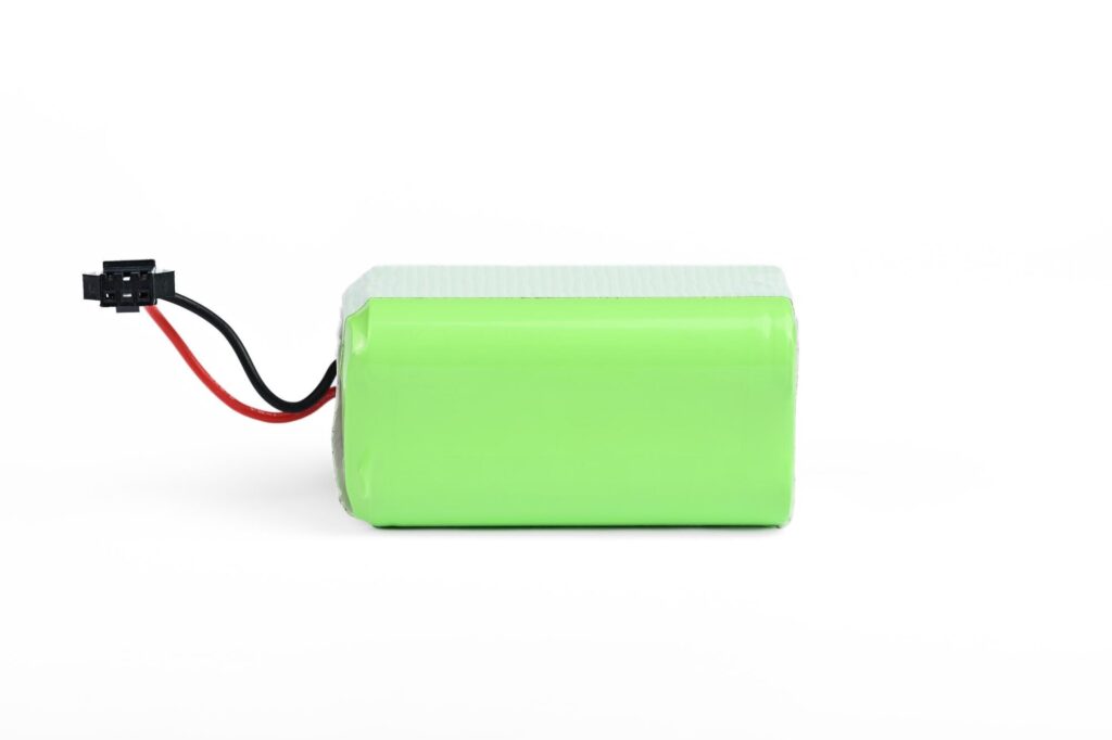 Grüner Lithium-Akkupack mit Kabel und Stecker vor weißem Hintergrund