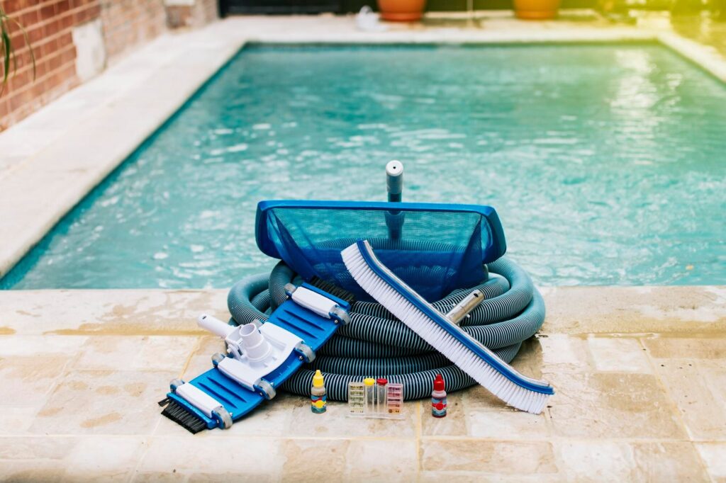 Poolpflege-Set mit Saugkopf, Schlauch, Kescher, Bürste und Teststreifen am Beckenrand