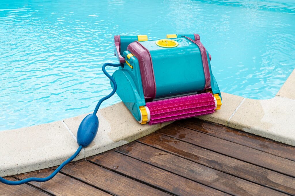 Poolroboter mit Bürstenwalze und Schwimmkabel am Beckenrand