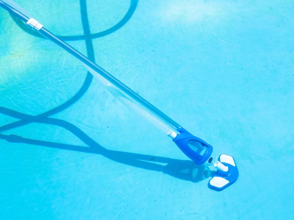 Poolsauger mit Schmutzkammer an der Stange am hellblauen Poolboden