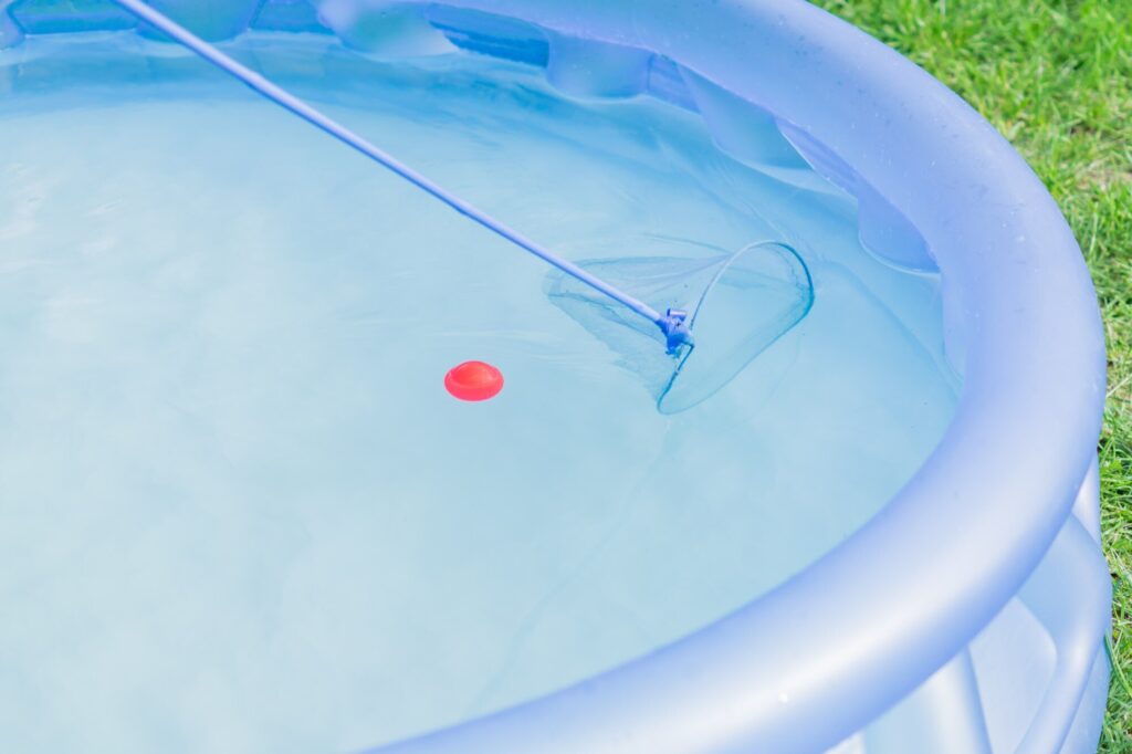 Kescher an der Stange im Wasser eines Quick-up-Pools mit aufblasbarem Ring