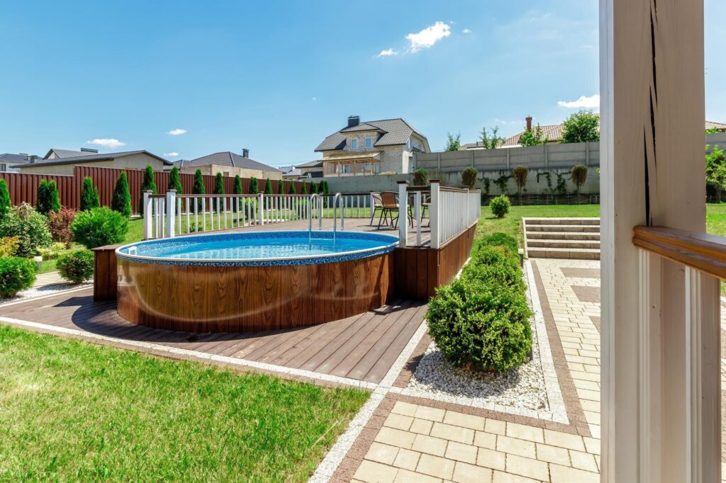 Runder Stahlwandpool mit Holzdekor an einer Holzterrasse im Garten