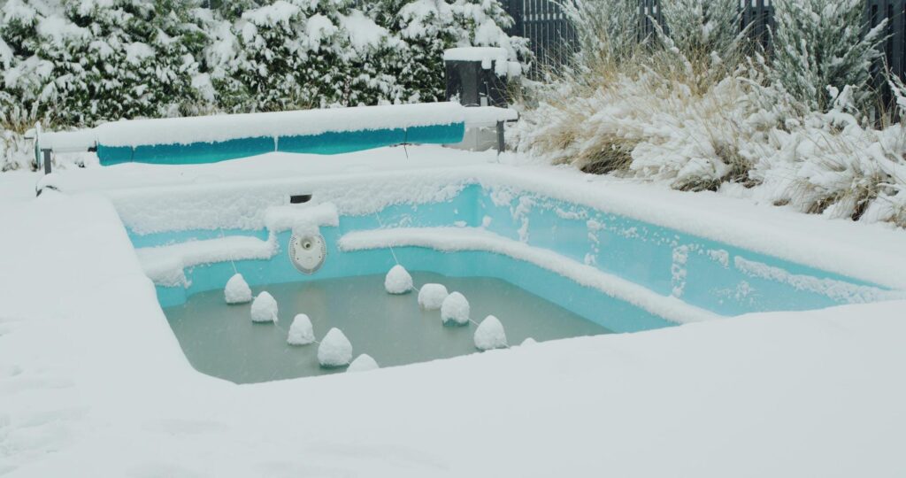 Eingewinterter Pool mit Eisdruckpolstern unter einer Schneedecke