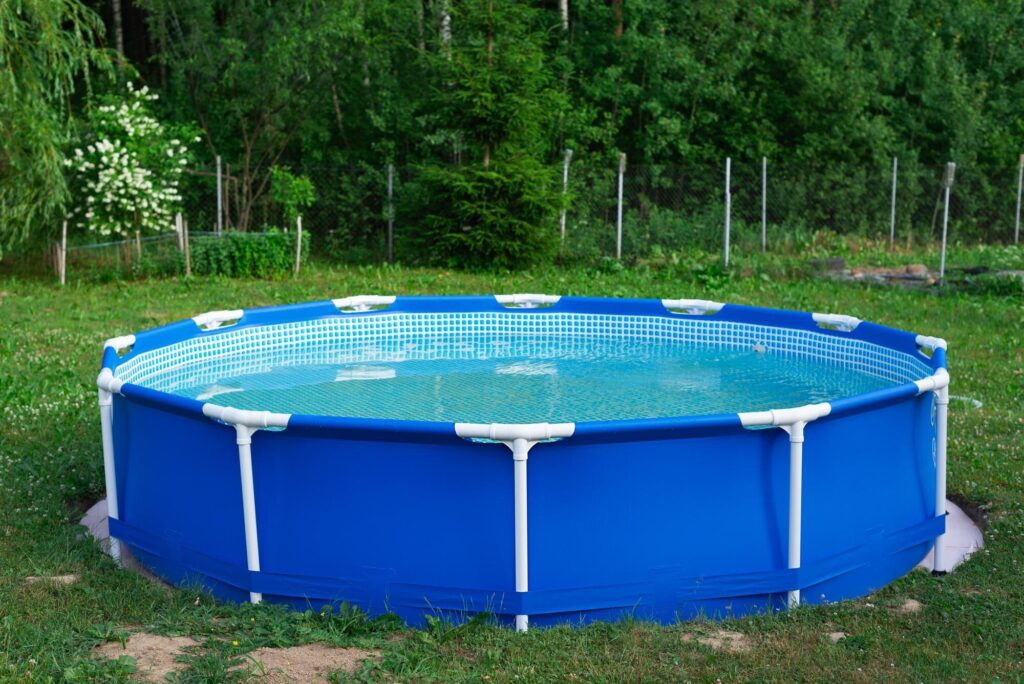 Kleiner blauer Aufstellpool mit Metallrahmen auf dem Rasen