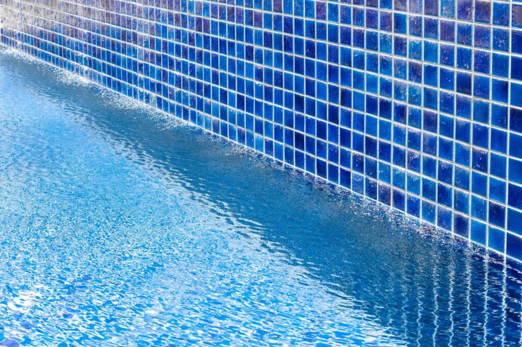 Wasseroberfläche entlang einer blau gefliesten Beckenwand
